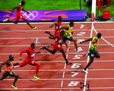 Athletics: sprinters cross the finish line in numbered lanes on the track.