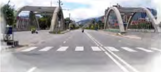 A modern town road with wide lanes, a zebra crossing and arched gateways.