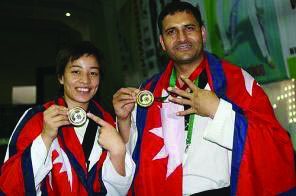 Two Nepali martial arts players wrapped in the national flag, showing their international medals. Athletes like these make their country known abroad.