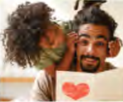 A child hugs her father, who holds a card with a red heart: a Father's Day scene.