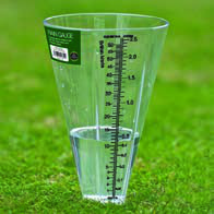 A rain gauge standing in the open, collecting rainfall against a marked scale so the amount can be read off.