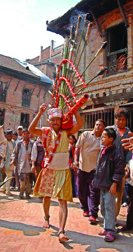 A devotee carries tall decorated poles through the streets during a festival procession in Nepal.