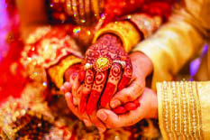 The bride's henna decorated hands joined with the groom's during a wedding ceremony.