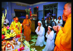 Monks and family members in white praying together at a funeral ceremony.