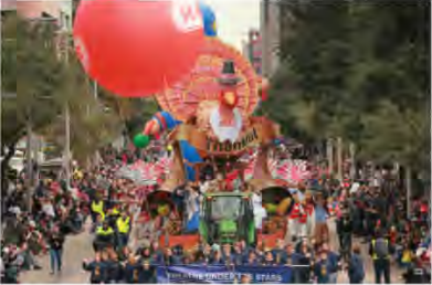 A giant float and balloon move through a crowded street in a Thanksgiving parade in the USA.