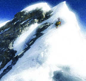 A climber nears the snowy summit of a high mountain.