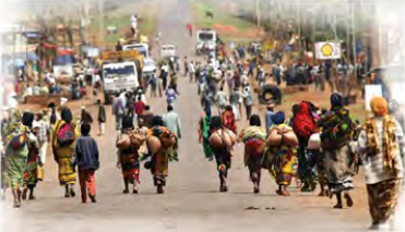 Families walking along a road with their belongings on their heads: people forced to migrate by conflict or hardship.