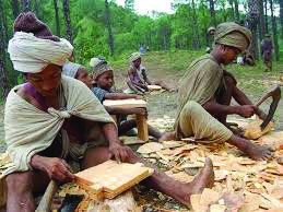 Raute men shaping wooden utensils by hand, the craft they trade in the market for food grains.