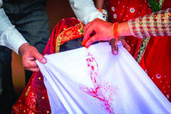 Red vermilion powder is passed along a white cloth, a solemn moment in a Hindu wedding.