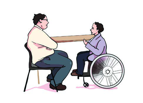 Mike interviews John across a table. John answers from his wheelchair, calm and ready.