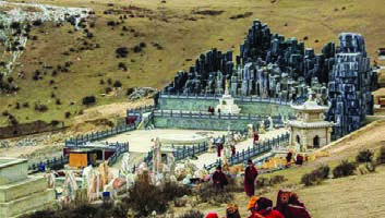 A sky burial ground near a monastery on a Tibetan hillside, ringed by walls, monuments and prayer flags.