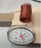 A spring-shaped copper coil with a magnetic compass placed beside one end