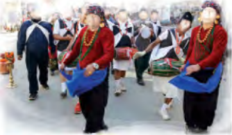 A community dance in traditional dress, with drums, performed through the street at a festival.